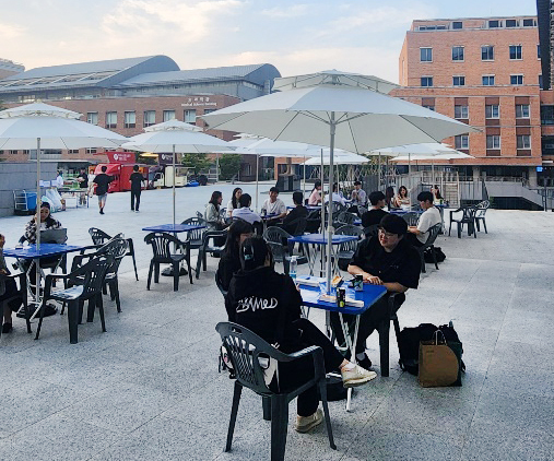 도서관 앞에서 담소를 나누며 음식을 먹는 학생들